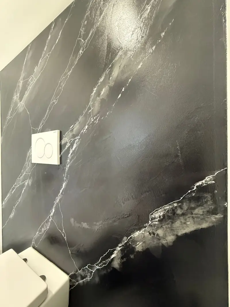 Detail van handgezette zilverwitte marmeraders in een antraciet marmerwand
